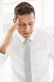 Young businessman with severe headache in office