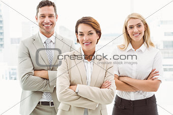 Happy business people with arms crossed in office