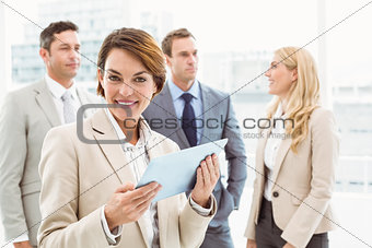 Businesswoman using digital tablet with colleagues behind