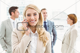 Businesswoman using mobile phone with colleagues behind