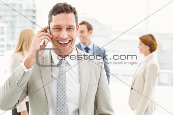 Businessman using mobile phone with colleagues behind