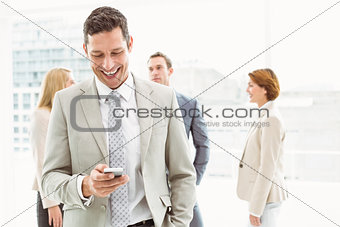 Businessman text messaging with colleagues in meeting behind
