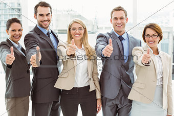Business people gesturing thumbs up in office