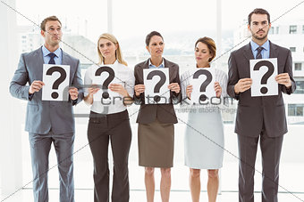 Business people holding question mark signs