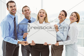Cheerful business people holding blank board in office