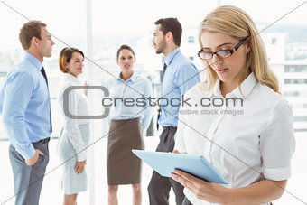 Businesswoman using digital tablet with colleagues behind