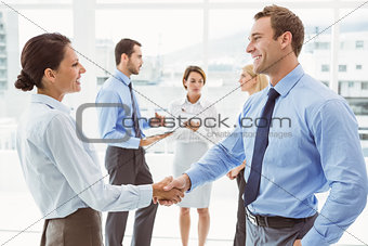 Executives shaking hands with colleagues behind