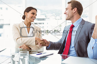 Executives shaking hands in board room meeting
