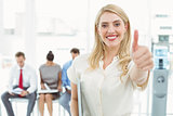 Businesswoman gesturing thumbs up against people waiting for interview
