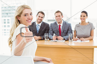 Woman gesturing thumbs up in front of corporate personnel officers