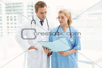 Male doctor and surgeon looking at reports