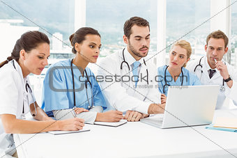 Male and female doctors using laptop