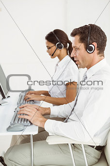 Business people with headsets using computers in office