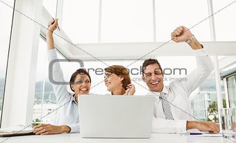 Business people cheering in front of laptop at office