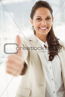 Businesswoman gesturing thumbs up in office
