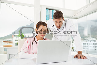 Doctors using laptop together at medical office