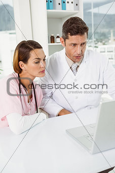 Doctors using laptop together at medical office