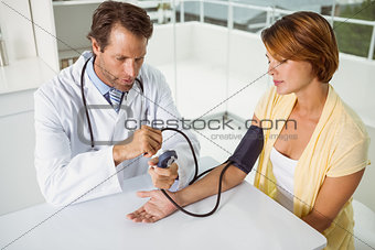 Doctor checking blood pressure of woman at medical office