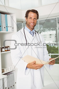 Confident smiling doctor with reports at medical office