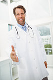 Smiling doctor offering handshake at medical office