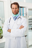Serious doctor with arms crossed in medical office