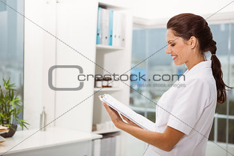 Smiling female doctor holding clipboard in medical office