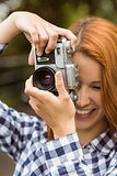 Pretty redhead taking a picture with retro camera