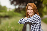 Gorgeous smiling redhead leaning against bridge