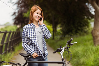 Smiling woman making a phone call in front of her bike