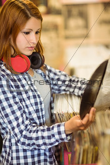 Redhead with a headphone around the neck holding a vinyl
