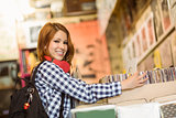 Pretty redhead searching a vinyl and smiling at camera