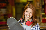 Portrait of a smiling redhead holding her skateboard