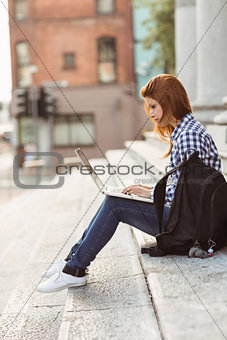 Young student using her laptop to study outside