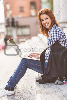 Portrait of a woman using her laptop and smiling at camera