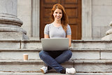 Smiling woman with disposable cup using laptop