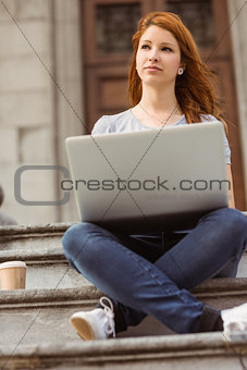 Day dreaming cute redhead using laptop