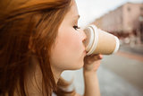 Pretty redhead drinking from disposable cup
