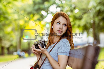 Redhead sitting on bench using her camera