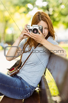 Redhead sitting on bench taking a photo