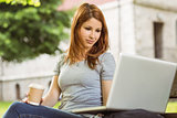 Woman with disposable cup and laptop sitting on bench