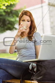 Girl sitting on bench drinking from disposable cup