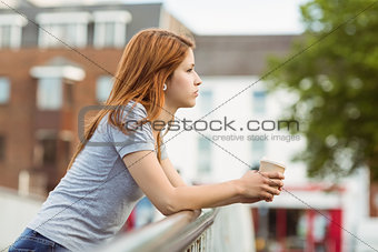 Woman with coffee cup day dreaming on the bridge