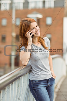 Smiling woman leaning on the bridge making a phone call