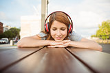 Woman lying on bench listening to music with eyes closed