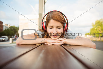 Woman lying on bench listening to music with eyes closed