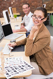 Smiling photo editors using computers in office