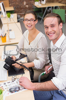 Casual photo editors with camera in office