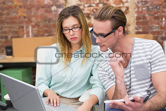 Colleagues using laptop in office