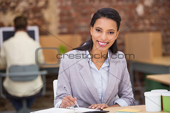 Smiling businesswoman writing diary in office