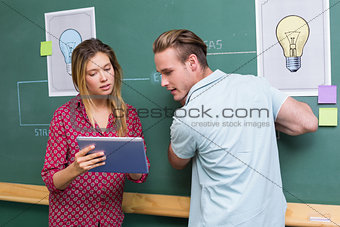 Creative business people with digital tablet by blackboard